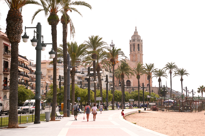 Die Strandpromenade von Sitges mit der Kirche San Bartomeu i Santa Tecla und dem Strand Platja de la Fragata
