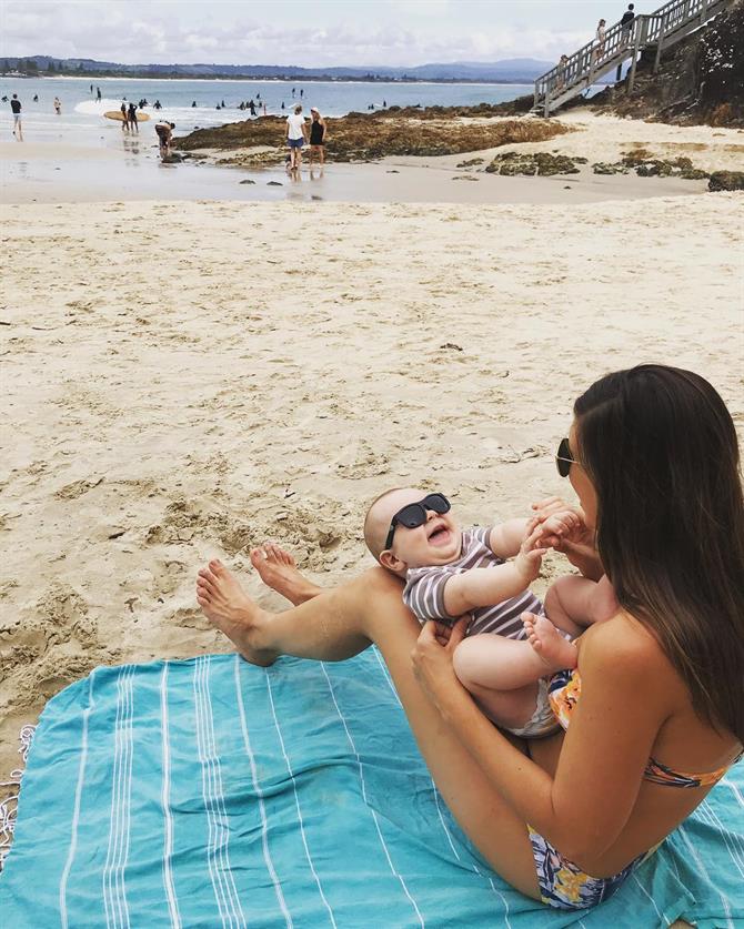 Mor på stranden med baby