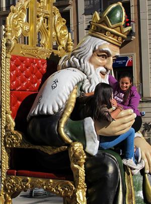 Giggling girls sit on the massive majestic King in Alicante province